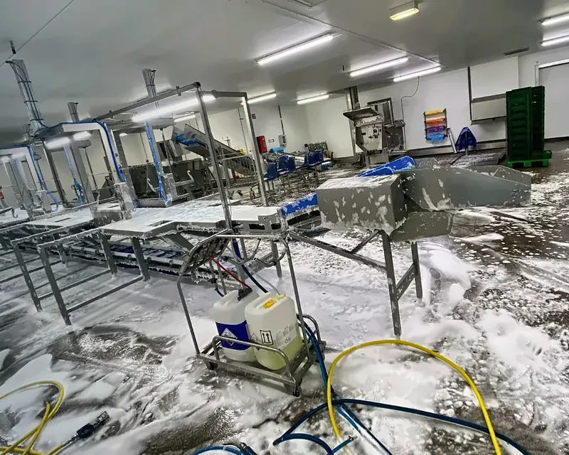 Productiehal tijdens de reiniging, ingezeept met schuim, met een kar met reinigingsmiddelen